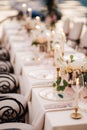 Wedding dinner table reception. Close-up of wildcard with gold beads, transparent glass. Runner of pink silk. Candles in Royalty Free Stock Photo