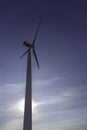 Close up of a windmill. Blue sky and the sun in the background. Vertical photograph. Renewable energies. Environmental protection