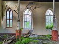 CLOSE UP: Windows are broken and facade decays inside an abandoned church. Royalty Free Stock Photo