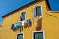 Close-up of windows on colorful walls and clothes hanging in an alley in Burano. Royalty Free Stock Photo