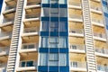 A close-up of the windows of a tall multi-storey building in blue and beige with glazed balconies.