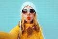 Close up winter portrait pretty woman blowing red lips sending sweet air kiss stretching hand for taking selfie Royalty Free Stock Photo