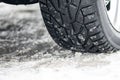 Close up winter tire or tyre of a car on the road covered by snow and ice Royalty Free Stock Photo