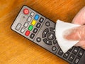 Close-up of wiping clean a TV hand remote control. With an antibacterial fabric tissue. To prevent germs, virus, bacteria and dirt
