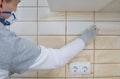 Close-up of wiping with a napkin after the process of grouting the cracks on the tile wall