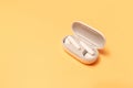 Close-up of wireless earbuds with charger case on pastel yellow background Royalty Free Stock Photo
