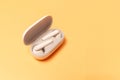 Close-up of wireless earbuds with charger case on pastel yellow background Royalty Free Stock Photo
