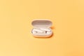 Close-up of wireless earbuds with charger case on pastel yellow background Royalty Free Stock Photo