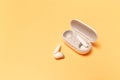 Close-up of wireless earbuds with charger case on pastel yellow background Royalty Free Stock Photo