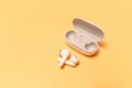 Close-up of wireless earbuds with charger case on pastel yellow background Royalty Free Stock Photo