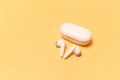 Close-up of wireless earbuds with charger case on pastel yellow background Royalty Free Stock Photo