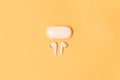 Close-up of wireless earbuds with charger case on pastel yellow background Royalty Free Stock Photo