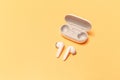 Close-up of wireless earbuds with charger case on pastel yellow background Royalty Free Stock Photo