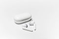 Close-up of wireless earphones lying near closed charging case on white background. Royalty Free Stock Photo