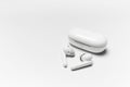 Close-up of wireless earphones lying near closed charging case on white background with copy space. Royalty Free Stock Photo