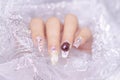 Close up woman acrylic fingernail painting beautiful white color gel nail art decorated with cute 3D rose flower sparkling