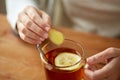 Close up of woman adding ginger to tea with lemon