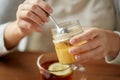 Close up of woman adding honey to tea with lemon