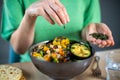 Close Up Of Woman Adding Pumpkin Seeds To Healthy Vegan Meal In Bowl