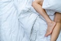 Close up woman bare feet on the bed over white blanket and bed sheet in the bedroom of home or hotel. Sleeping and relax concept. Royalty Free Stock Photo