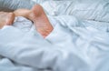 Close up woman bare feet on the bed over white blanket and bed sheet in the bedroom of home or hotel. Sleeping and relax concept Royalty Free Stock Photo