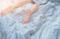 Close up woman bare feet on the bed over white blanket and bed sheet in the bedroom of home or hotel. Sleeping and relax concept Royalty Free Stock Photo