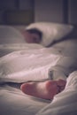 Close up woman bare feet on the bed over white blanket and bed sheet in the bedroom of home or hotel. Sleeping and relax concept. Royalty Free Stock Photo