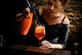 Close-up woman bartender attentively pours carbonated drink to glass with negroni cocktail. Royalty Free Stock Photo