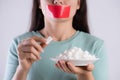 Close up woman beautiful hands holding white sugar cubes and close mouth by red tape. Healthcare concept Royalty Free Stock Photo