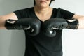 Close-up of woman in a black T-shirt and black boxing gloves hitting together