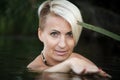 Close-up of a woman blonde middle-aged nude swims in the river, selective focus Royalty Free Stock Photo