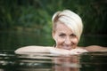 Close-up of a woman blonde middle-aged nude swims in the river, selective focus Royalty Free Stock Photo