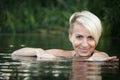 Close-up of a woman blonde middle-aged nude swims in the river, selective focus Royalty Free Stock Photo