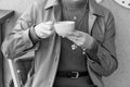 Close up woman with blue manicure holds a coffee cup with cappuccino. Black and white background Royalty Free Stock Photo