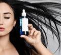 Close up of woman brunette with closed eyes and long hair fluttering in the strong wind holds a bottle. Advertisement concept Royalty Free Stock Photo