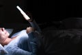 Close up of woman chatting and surfing on the internet with smartphone late at night in bed. Bored and sleepless in dark room with Royalty Free Stock Photo