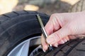 Close-up of woman checking tread on car tire with gauge