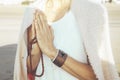 Close up of a woman clasping hands while holding a japa mala outdoors. Namaste pose.