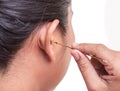 Close up woman cleaning her ear by using metal stick isolated on