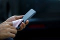 Close up of a woman cleaning mobile smart phone with fabric in dark background