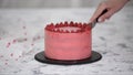 Close-up of woman confectioner cutting a raspberry cake.