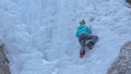 CLOSE UP: Woman with crampons and ice axes scales the gorgeous frozen waterfall.