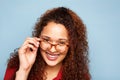 Close up woman with curly hair and glasses smiling against blue background Royalty Free Stock Photo