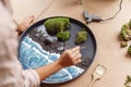 Close up of woman decorator making green ikebana on tray with epoxy resin in florist workshop