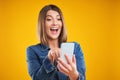 Close up of woman in denim jacket with smartphone over yellow background Royalty Free Stock Photo