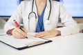 Close-up of woman doctor in office filling out application form at the table Royalty Free Stock Photo