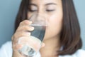 Close up woman drinking pure water from glass with blue background, Selective focus Royalty Free Stock Photo