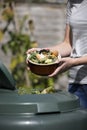 Close Up Of Woman Emptying Food Waste Into Garden Composter At Home