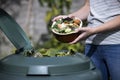 Close Up Of Woman Emptying Food Waste Into Garden Composter At Home