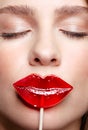 Close-up of woman with eyes closed kissing candy. Red female lips shape lollipop. Sweet tooth concept Royalty Free Stock Photo